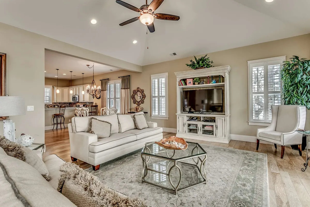 A cozy living area accented by a plush sofa, a central coffee table, a television for entertainment, and a touch of greenery from a potted plant. The space exudes warmth and comfort, ready for movie nights, game sessions, or relaxed evenings spent in good company.
