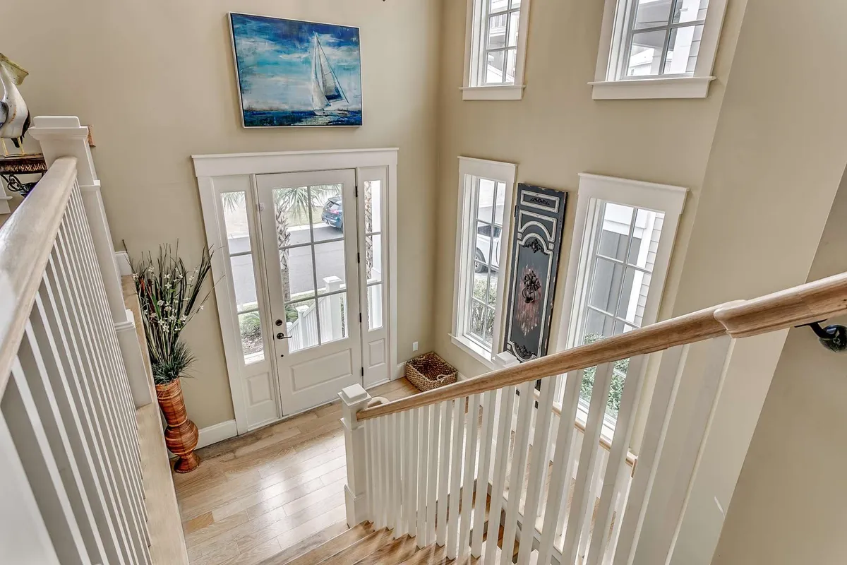 The inviting entryway of the home features a stylish staircase, a painting of a sailboat, and ample windows allowing natural light to stream in. The front door area signals a warm welcome, setting the tone for both arrival and departure as guests head out to explore local attractions.