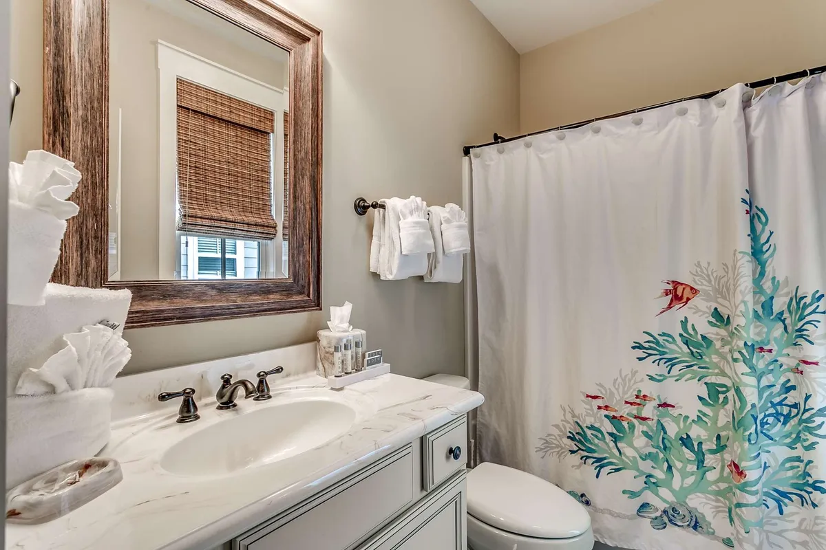 A fresh and clean bathroom interior featuring a mirror, sink, and shower curtain. The space feels inviting and well-equipped for personal grooming and relaxation after a day of adventure.